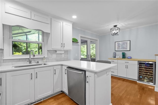 kitchen featuring beverage cooler, a sink, dishwasher, a peninsula, and white cabinetry