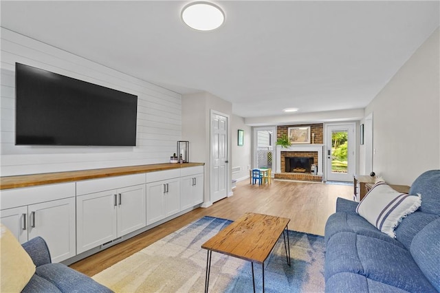 living area featuring light wood-type flooring and a brick fireplace