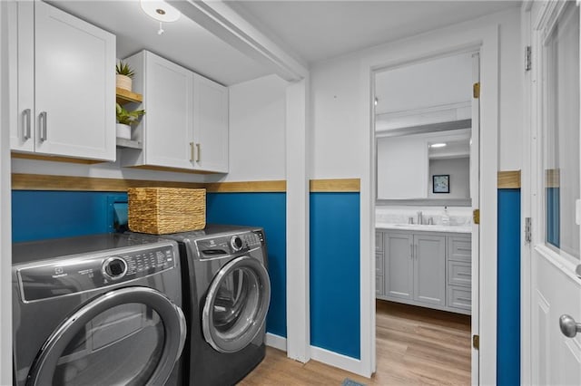 laundry area with cabinet space, light wood-style flooring, and washer and dryer