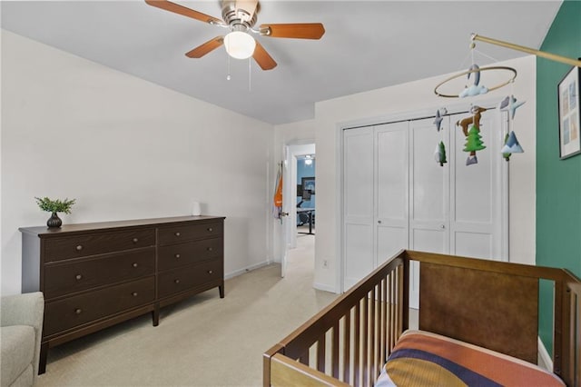 bedroom featuring light colored carpet, a closet, baseboards, and a ceiling fan