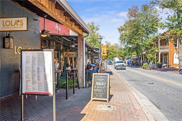 view of asphalt street with curbs, sidewalks, and street lighting