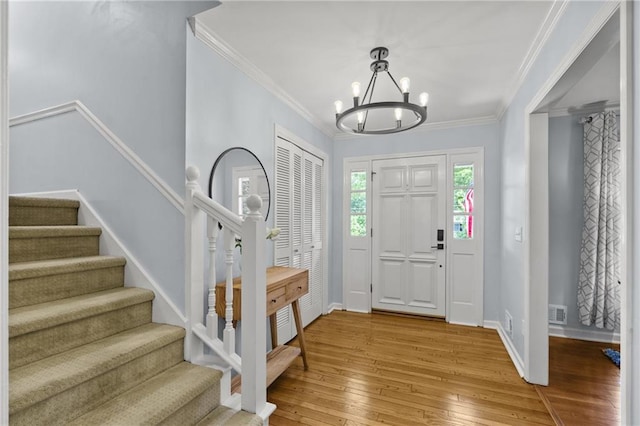 foyer featuring a chandelier, stairs, light wood finished floors, baseboards, and crown molding