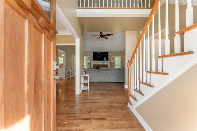 foyer with ceiling fan, wood finished floors, stairway, and a fireplace