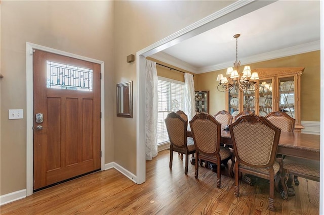 dining area featuring baseboards, light wood finished floors, crown molding, and a notable chandelier