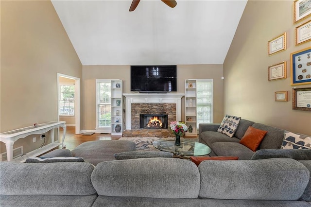 living area with wood finished floors, a fireplace, baseboards, ceiling fan, and high vaulted ceiling