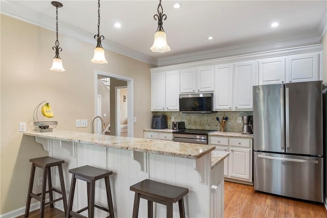 kitchen with white cabinets, appliances with stainless steel finishes, a peninsula, light wood-type flooring, and backsplash