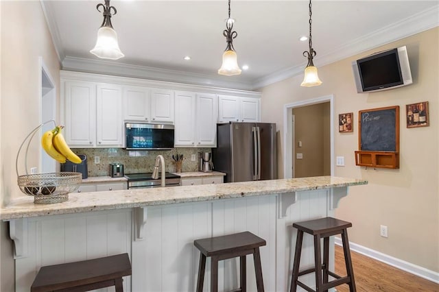 kitchen featuring white cabinets, stainless steel appliances, a breakfast bar area, and tasteful backsplash