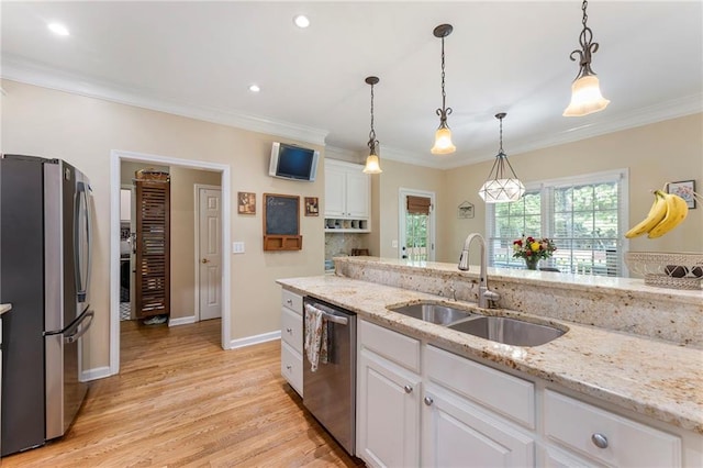 kitchen featuring a sink, white cabinets, ornamental molding, stainless steel appliances, and light wood-style flooring
