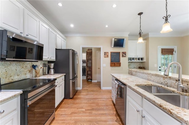 kitchen featuring appliances with stainless steel finishes, a sink, white cabinetry, decorative backsplash, and ornamental molding