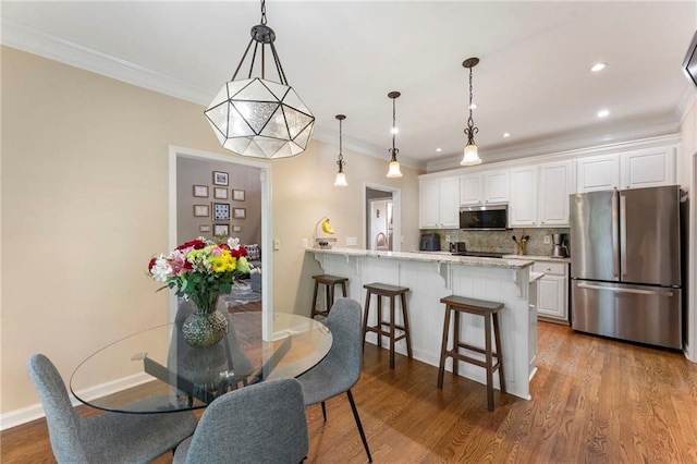 dining space featuring baseboards, ornamental molding, recessed lighting, and wood finished floors