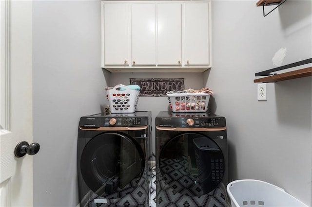 clothes washing area featuring washing machine and dryer and cabinet space