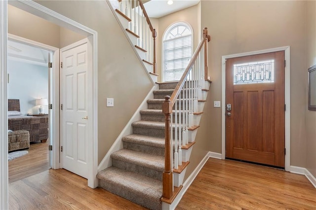 entryway featuring light wood-style floors, baseboards, and stairway