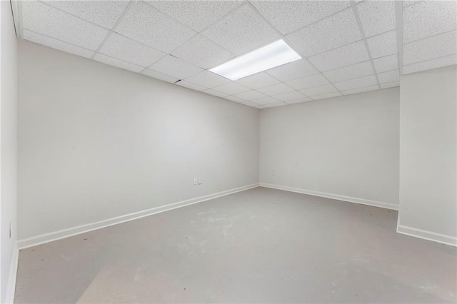 unfurnished room featuring baseboards, concrete flooring, and a drop ceiling