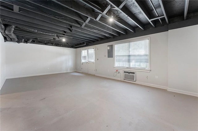 basement featuring baseboards, electric panel, and an AC wall unit