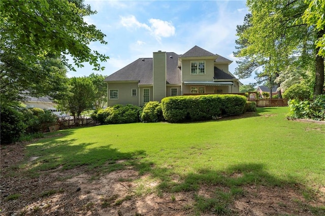 back of property with a lawn, fence, and a chimney