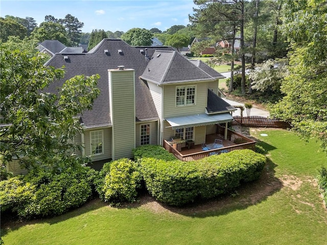 rear view of property featuring a yard, a deck, fence, and a shingled roof