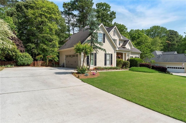 view of front of home featuring a front yard, fence, concrete driveway, an attached garage, and stucco siding