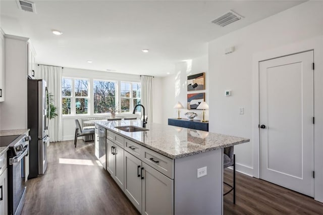 kitchen with a sink, stainless steel appliances, visible vents, and a breakfast bar