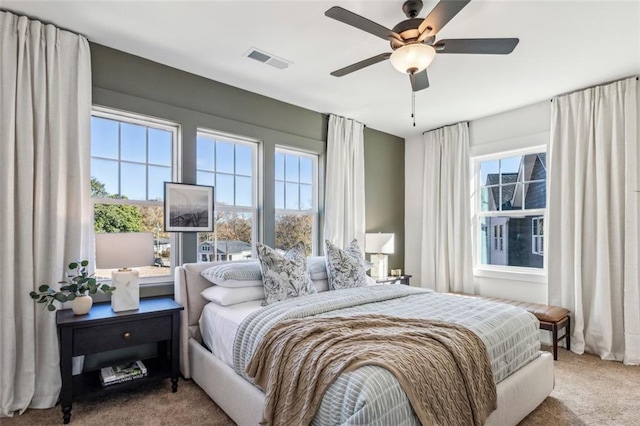 bedroom with multiple windows, carpet flooring, visible vents, and ceiling fan