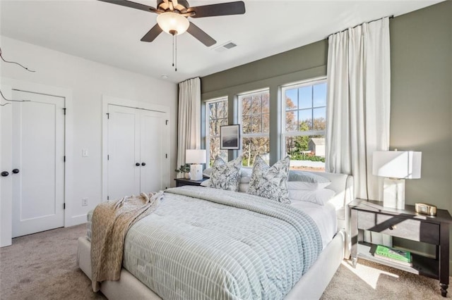 bedroom featuring visible vents, ceiling fan, multiple closets, and carpet floors