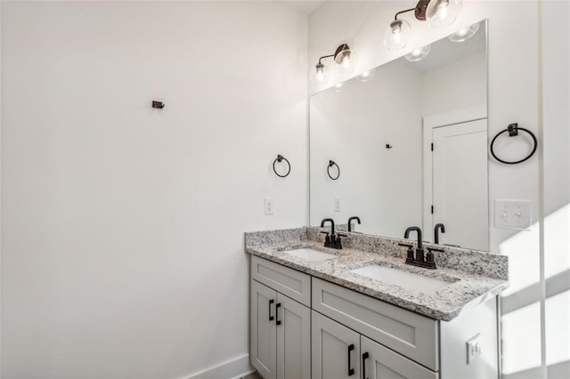 bathroom with double vanity, baseboards, and a sink