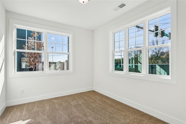 unfurnished room with carpet, visible vents, and baseboards