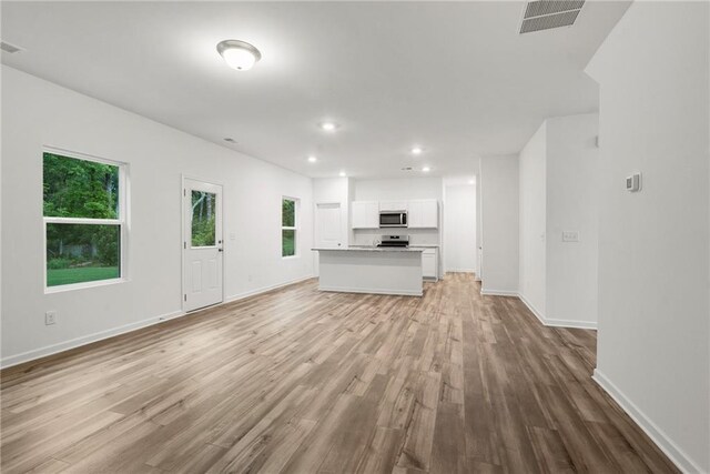 kitchen with white cabinetry, a healthy amount of sunlight, stainless steel appliances, and light hardwood / wood-style flooring