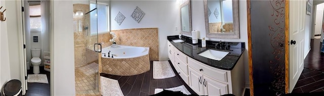 full bath featuring vanity, wood finished floors, a stall shower, a garden tub, and toilet