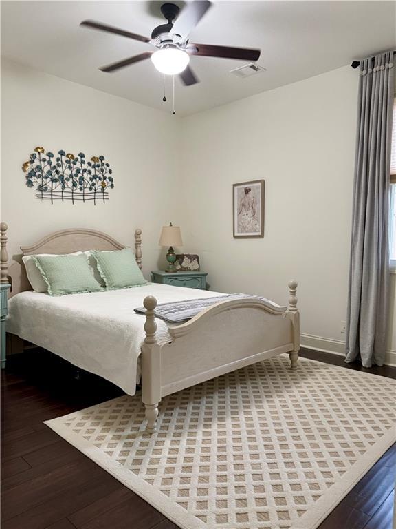 bedroom featuring visible vents, baseboards, wood finished floors, and a ceiling fan