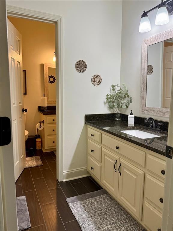 bathroom with vanity, toilet, baseboards, and wood tiled floor