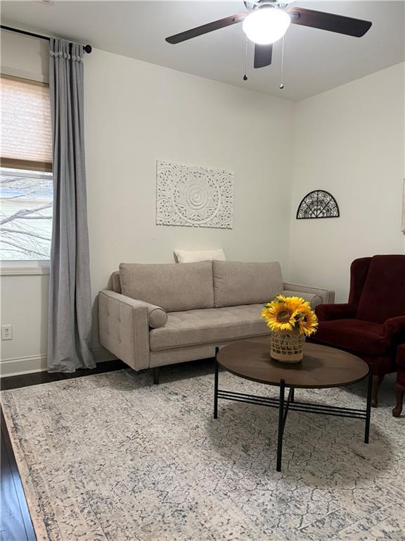 living room featuring baseboards, wood finished floors, and a ceiling fan