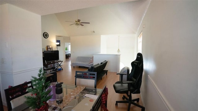 interior space featuring ceiling fan, high vaulted ceiling, light hardwood / wood-style floors, and a textured ceiling