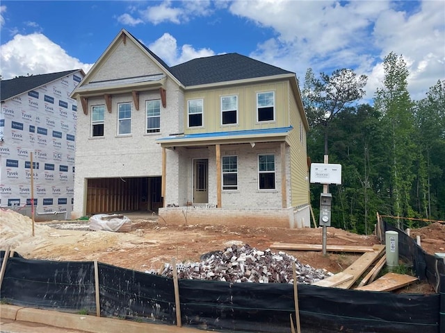unfinished property with an attached garage, brick siding, and fence
