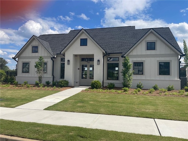 modern farmhouse style home featuring a shingled roof, board and batten siding, brick siding, and a front lawn