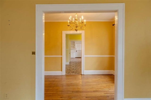 interior space featuring hardwood / wood-style flooring, crown molding, and a notable chandelier