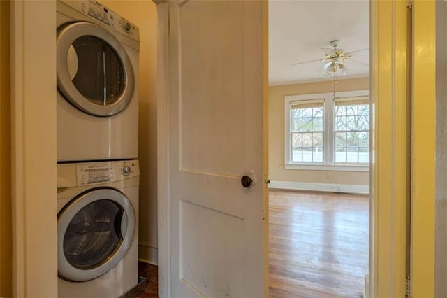 clothes washing area with hardwood / wood-style flooring, stacked washer / dryer, and ceiling fan