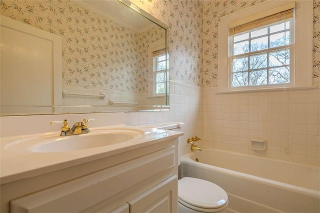 bathroom featuring a wealth of natural light, vanity, a bathtub, and toilet