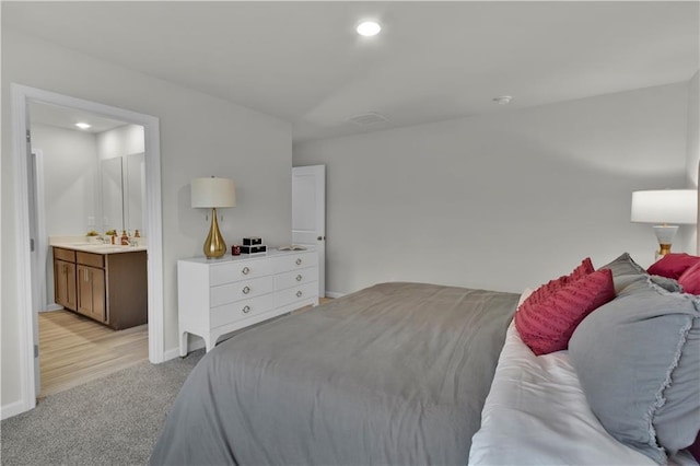 bedroom with baseboards, light colored carpet, ensuite bath, a sink, and recessed lighting