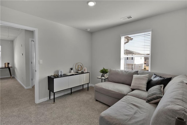 living area featuring light carpet, attic access, visible vents, and baseboards