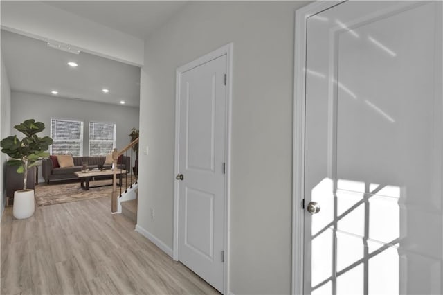 hallway with stairs, baseboards, light wood-style flooring, and recessed lighting