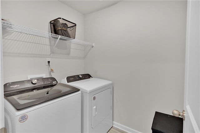 laundry area with light wood-type flooring, laundry area, baseboards, and washing machine and clothes dryer