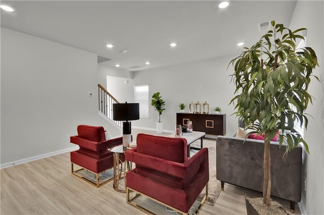 living area featuring baseboards, visible vents, stairway, light wood-type flooring, and recessed lighting