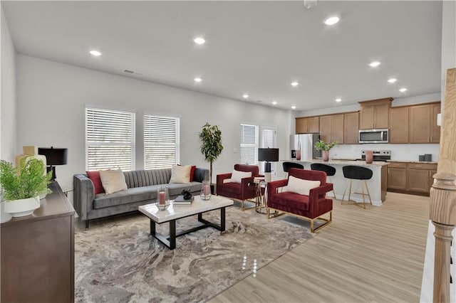 living room featuring light wood-style floors, recessed lighting, and visible vents