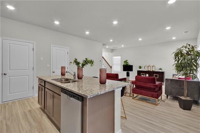 kitchen featuring light wood finished floors, recessed lighting, stainless steel dishwasher, a sink, and an island with sink