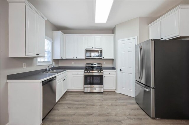 274 Sleepy Hollow Rd, Powder Springs, GA 30127 - kitchen with light wood-type flooring, stainless steel appliances, a sink, dark countertops, and white cabinets