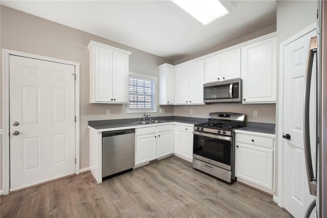 274 Sleepy Hollow Rd, Powder Springs, GA 30127 - kitchen with a sink, white cabinetry, light wood-type flooring, and appliances with stainless steel finishes