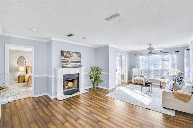 living room with ceiling fan, crown molding, hardwood / wood-style floors, and a textured ceiling