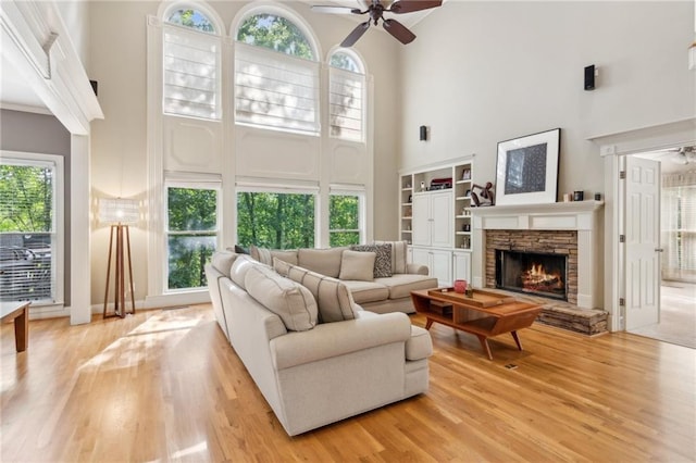 6795 Preston Glen Dr, Alpharetta, GA 30005 - living room featuring a towering ceiling, ceiling fan, light wood-style flooring, and a stone fireplace