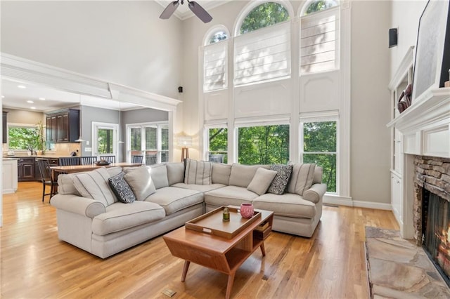 6795 Preston Glen Dr, Alpharetta, GA 30005 - living room with a high ceiling, a stone fireplace, ceiling fan, light wood-style flooring, and crown molding