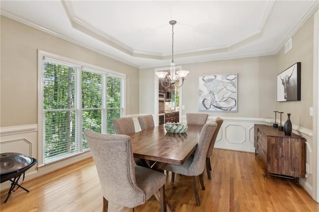 6795 Preston Glen Dr, Alpharetta, GA 30005 - dining area featuring a chandelier, a tray ceiling, light wood-style flooring, crown molding, and a decorative wall